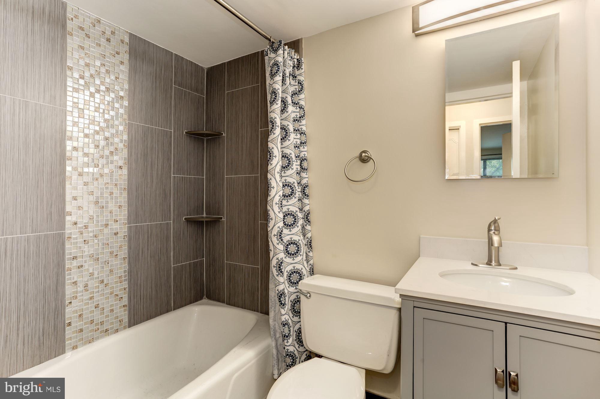 2501 Calvert Street Northwest, Unit 110 Washington, DC 20008 - Photo 23 of 28 New Tiles on Walls and Fl,, toilet and Gray vanity