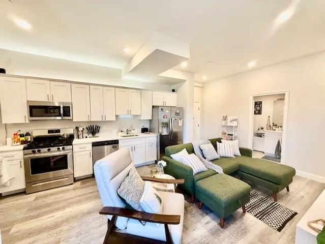 a living room with furniture white cabinets and stainless steel appliances