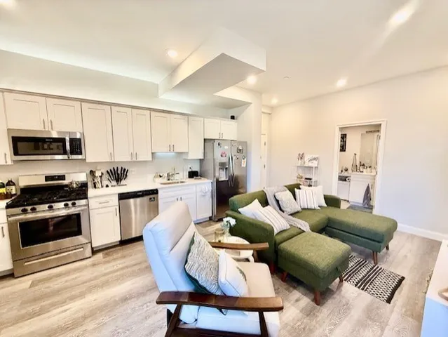 a living room with stainless steel appliances furniture and a kitchen view