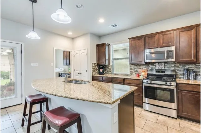 a kitchen with kitchen island granite countertop a stove a sink and a refrigerator