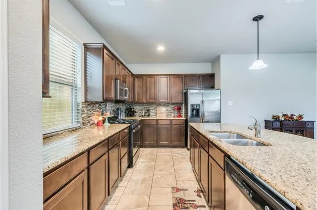 a kitchen with kitchen island granite countertop a sink counter top space appliances and cabinets