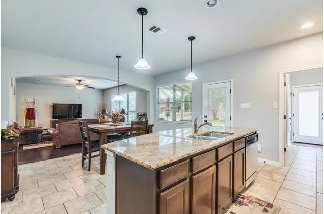 a open kitchen with stainless steel appliances granite countertop a stove a sink dishwasher and a table with chairs
