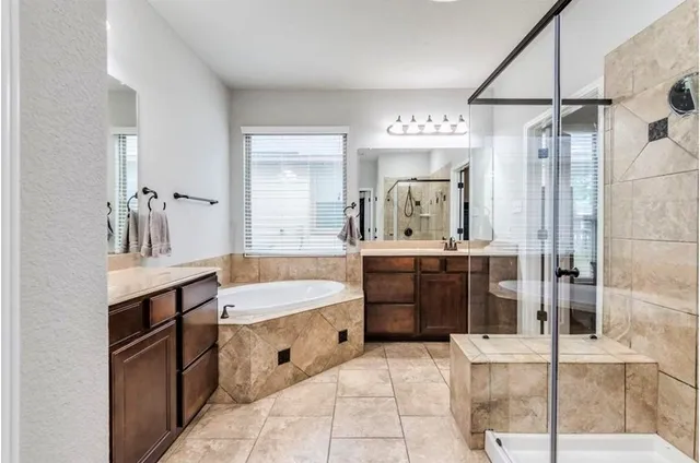 a spacious bathroom with a tub sink shower and mirror