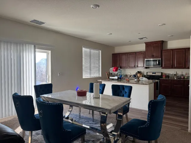 a kitchen with granite countertop a dining table chairs and a refrigerator