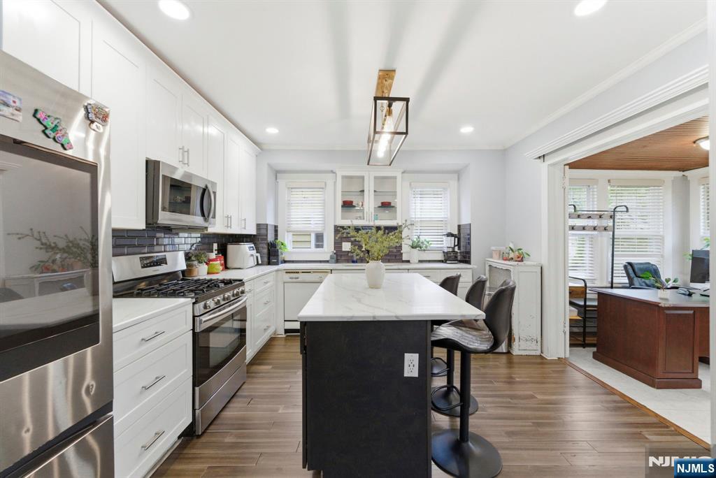105 Daniel Avenue Rutherford, NJ 07070 - Photo 6 of 38 a kitchen with stainless steel appliances granite countertop a stove top oven a sink dishwasher a dining table and chairs with wooden floor