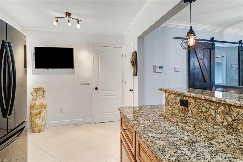 2329 41st Terrace Southwest Naples, FL 34116 - Photo 11 of 33 a kitchen with kitchen island a counter top space appliances and a refrigerator