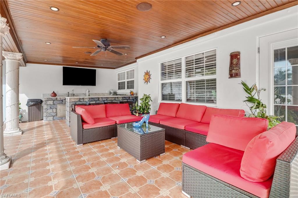 2329 41st Terrace Southwest Naples, FL 34116 - Photo 24 of 33 a living room with furniture a flat screen tv and a floor to ceiling window
