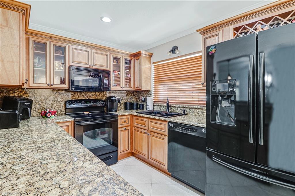 2329 41st Terrace Southwest Naples, FL 34116 - Photo 10 of 33 a kitchen with stainless steel appliances granite countertop a refrigerator and a stove top oven