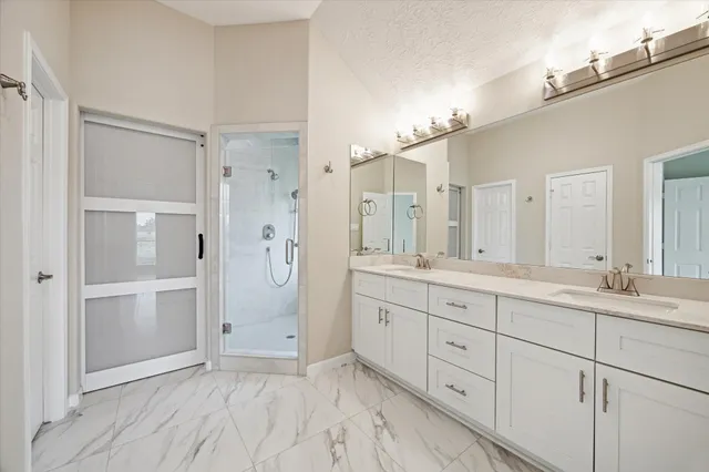 a spacious bathroom with a double vanity sink a shower and a mirror