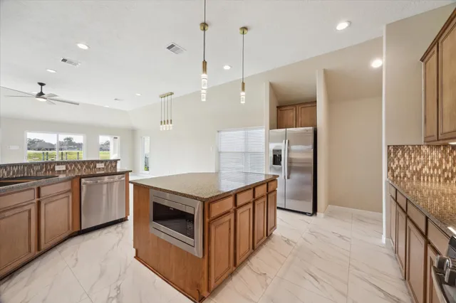 a kitchen with stainless steel appliances granite countertop a kitchen island a stove and a refrigerator