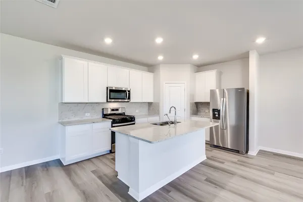 a kitchen with stainless steel appliances granite countertop a refrigerator oven a sink dishwasher and a stove with wooden floor