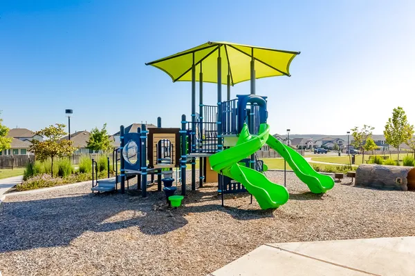 a view of a park with a slide and potted plants