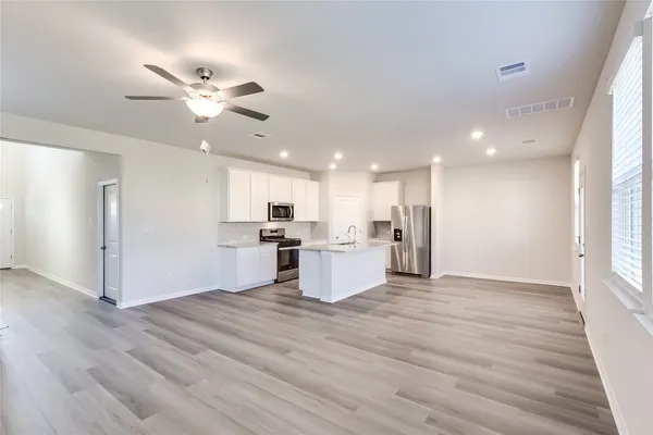 a view of a kitchen with kitchen island wooden floor center island and stainless steel appliances