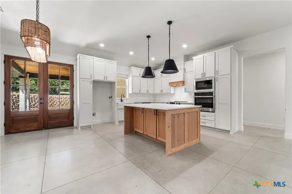 a kitchen with kitchen island granite countertop a stove a sink a refrigerator and a counter top space