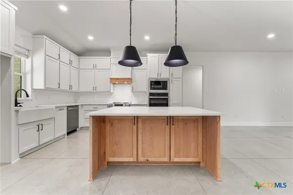 a kitchen with kitchen island white cabinets stainless steel appliances and a chandelier