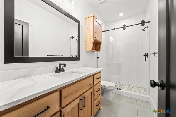 a bathroom with a sink a toilet a mirror and shower