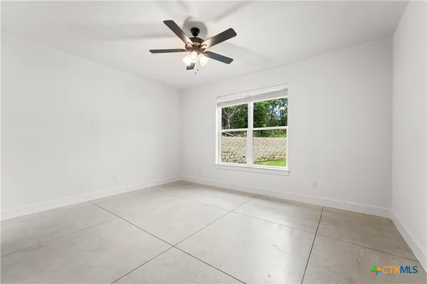 an empty room with windows and ceiling fan