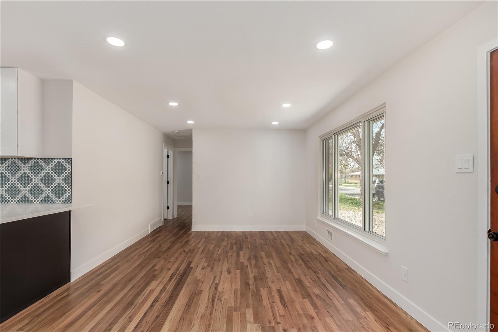 2702 Atchison Street Aurora, CO 80011 - Photo 4 of 18 an empty room with wooden floor and windows