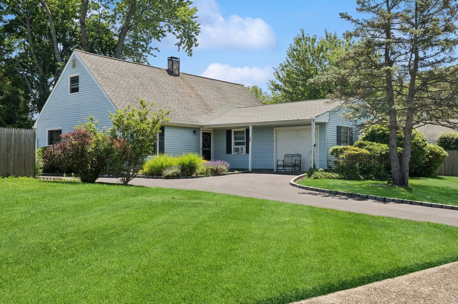 View of front facade featuring a garage, a chimney, driveway, and a shingled roof