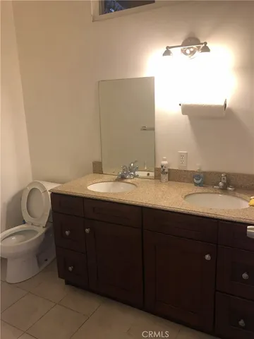 a bathroom with a granite countertop sink and a toilet