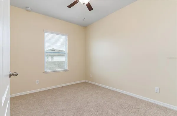 an empty room with a window and a fan