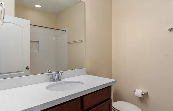 a bathroom with a granite countertop sink toilet and a mirror