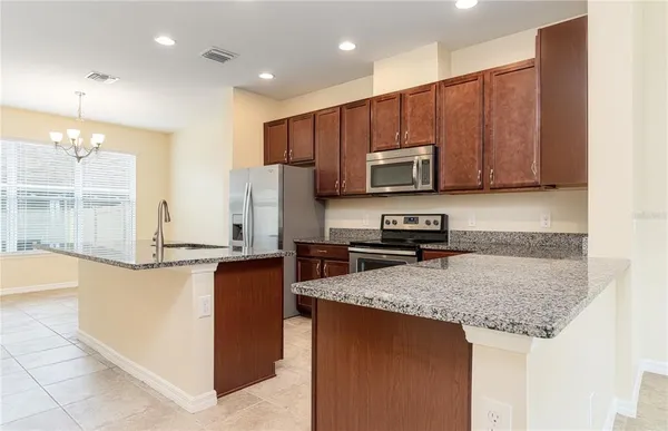 a kitchen with kitchen island granite countertop wooden cabinets a refrigerator and a sink