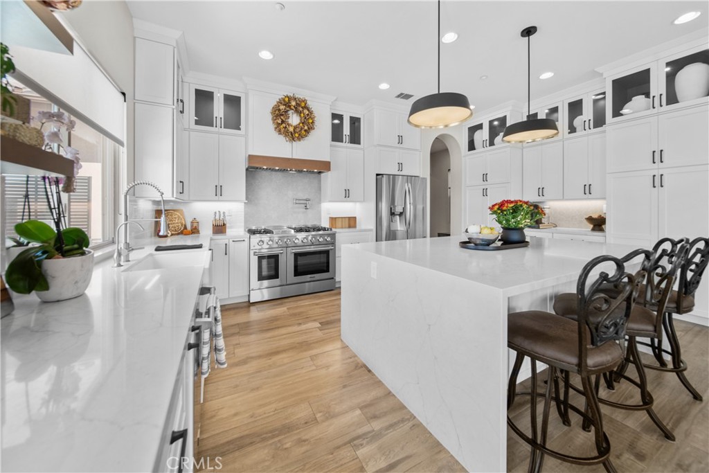 169 Mission Oaks Road Fallbrook, CA 92028 - Photo 16 of 35 a kitchen with stainless steel appliances granite countertop a stove top oven a sink a dining table and chairs with wooden floor