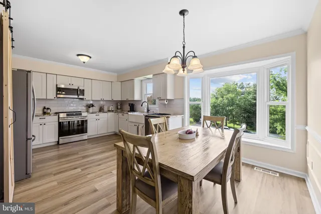 a view of a dining room and livingroom with furniture wooden floor a chandelier