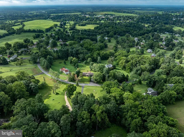 an aerial view of a houses with outdoor space and trees all around