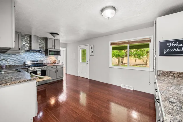 a kitchen with stainless steel appliances granite countertop a stove top oven a sink and a refrigerator