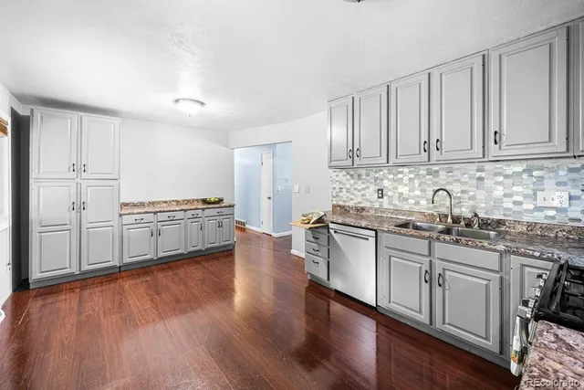 a kitchen with stainless steel appliances granite countertop a stove top oven a sink and white cabinets with wooden floor