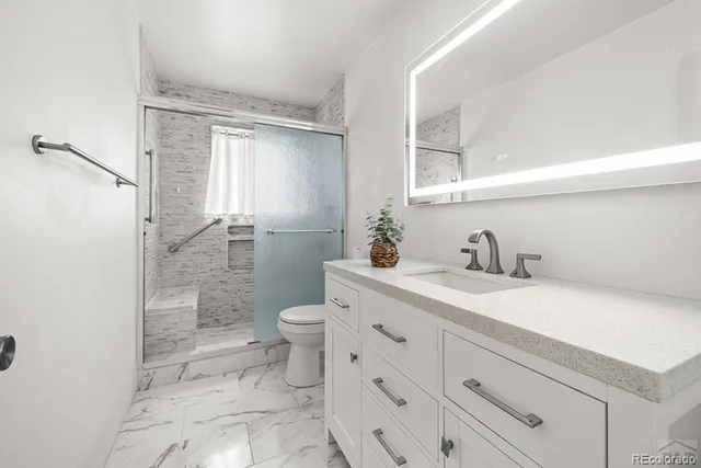 a bathroom with a granite countertop sink mirror vanity and toilet