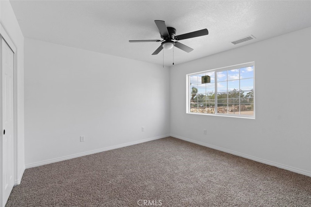 14685 Apple Valley Road Apple Valley, CA 92307 - Photo 18 of 29 an empty room with a window and a fan
