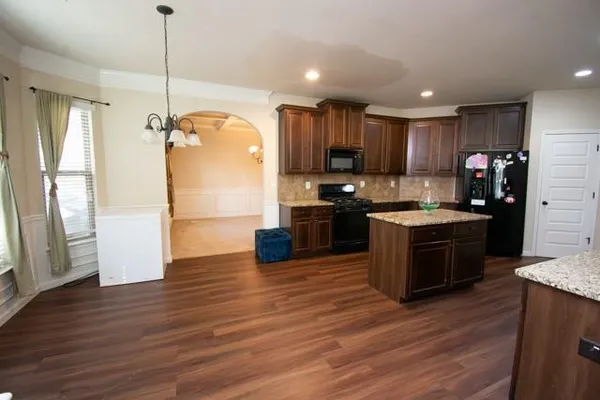 a kitchen with kitchen island granite countertop wooden floors stainless steel appliances a sink and a window