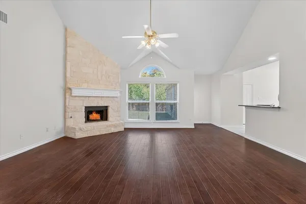 a view of an empty room with wooden floor fireplace and a window