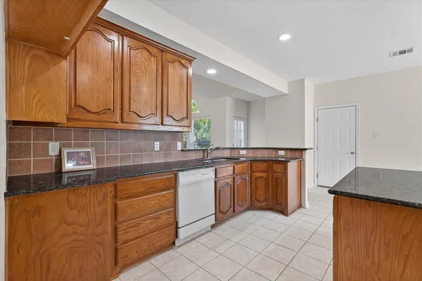 a kitchen with granite countertop a sink window and cabinets