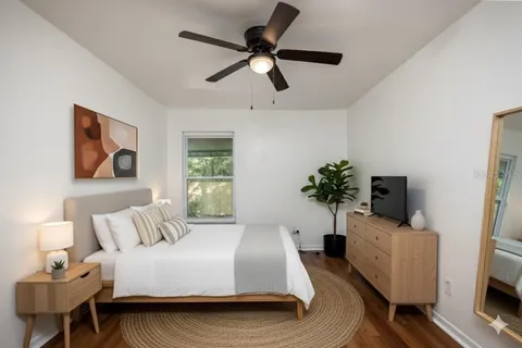 an empty room with wooden floor ceiling fan and windows
