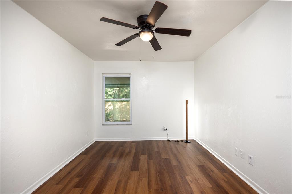 6708 Southwest 45th Avenue Gainesville, FL 32608 - Photo 30 of 40 an empty room with wooden floor ceiling fan and windows