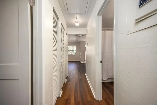an empty room with wooden floor closet and windows