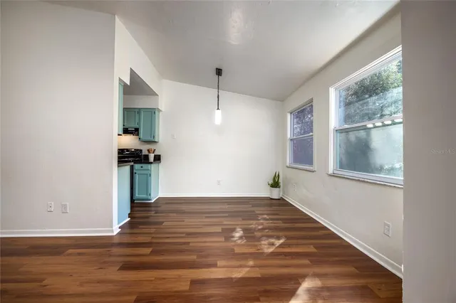 a view of an empty room with window and wooden floor