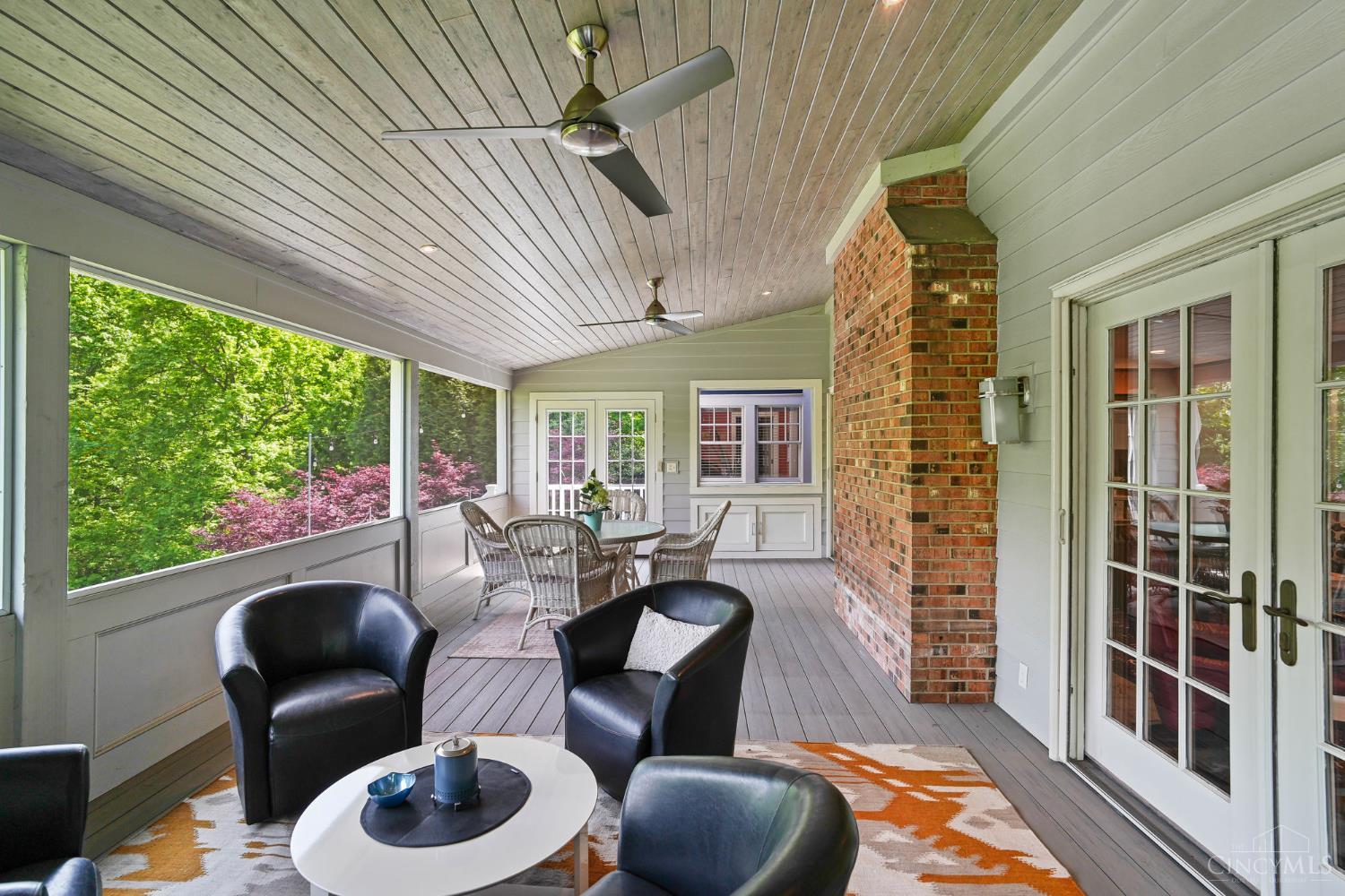 2780 Walsh Road Cincinnati, OH 45208 - Photo 7 of 68 The serene screened porch just off the family room offers the perfect extension of living space—featuring low-maintenance composite decking, a vaulted wood ceiling with ceiling fans and a striking brick accent wall. Designed for both dining and lounging, this inviting retreat is surrounded by lush, tree-lined views, creating a peaceful setting for relaxing or entertaining in every season.