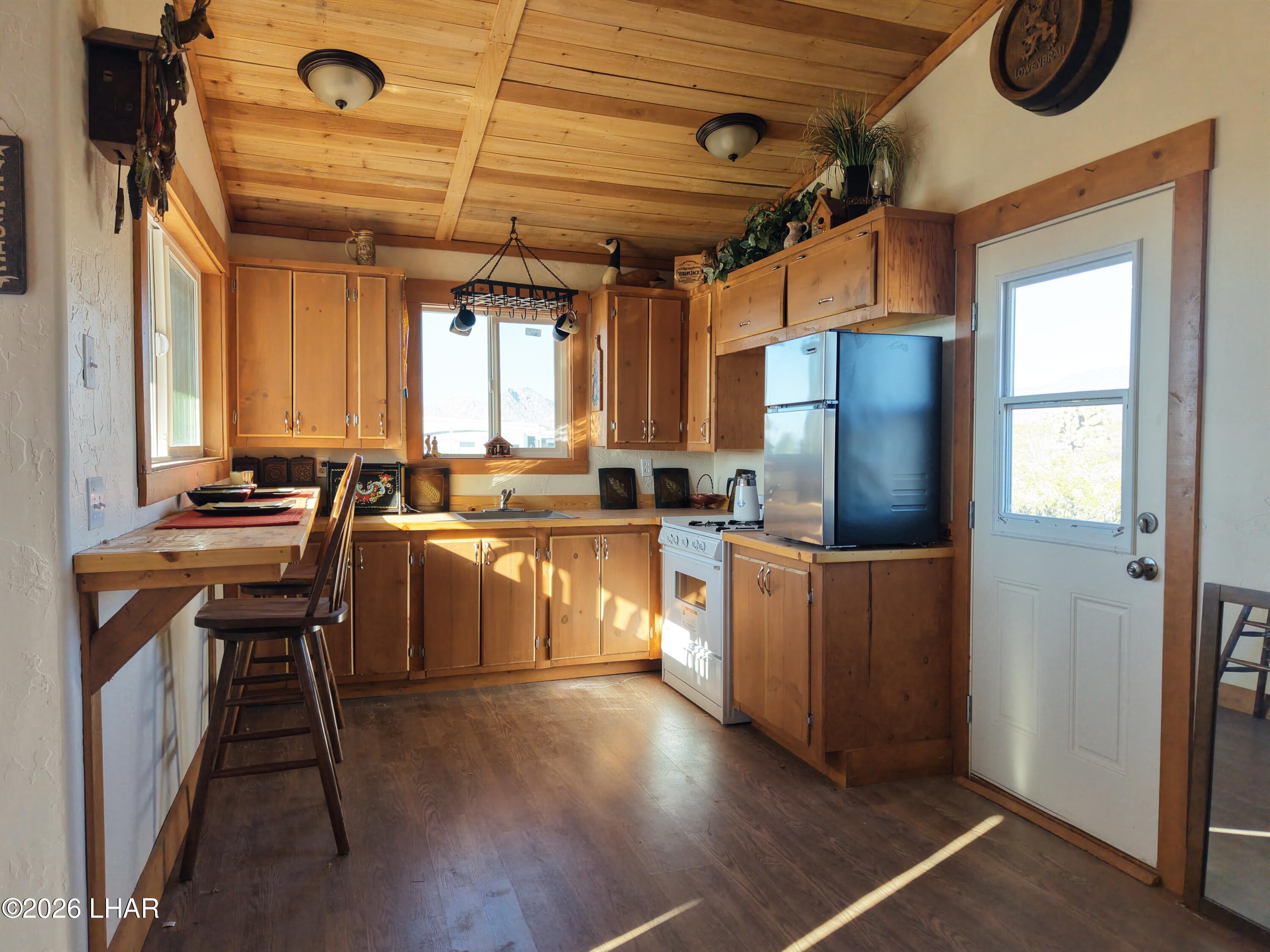 127 South Carrow Road Yucca, AZ 86438 - Photo 19 of 39 a kitchen with stainless steel appliances granite countertop a refrigerator a sink dishwasher a stove and a dining table with wooden floor