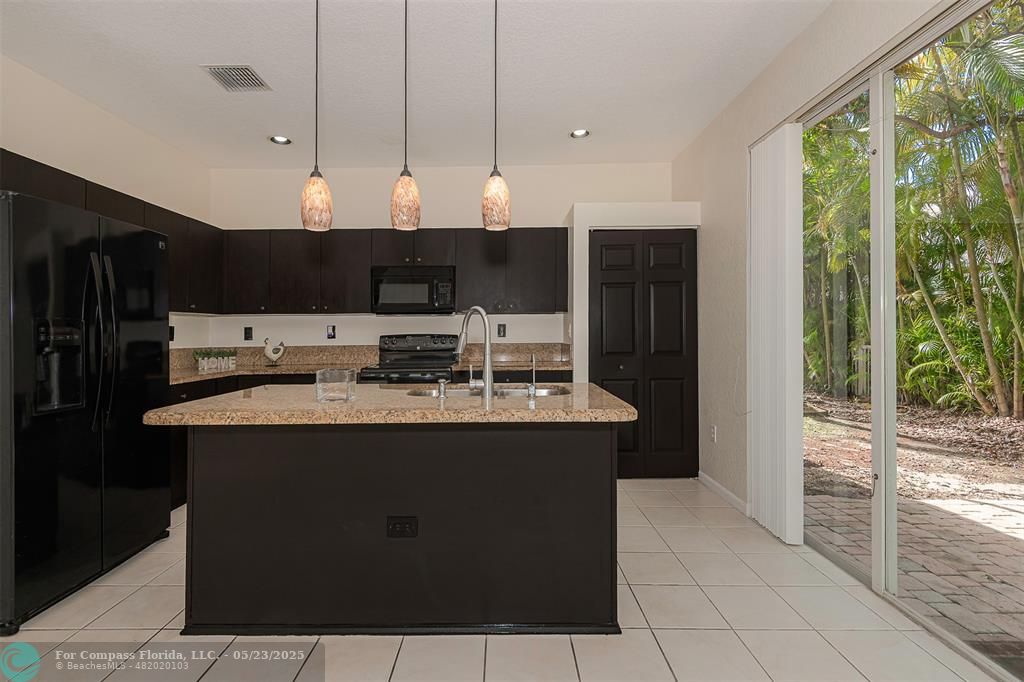 18798 Southwest 28th Street, Unit 18798 Miramar, FL 33029 - Photo 12 of 28 a room with kitchen island granite countertop a sink and a refrigerator