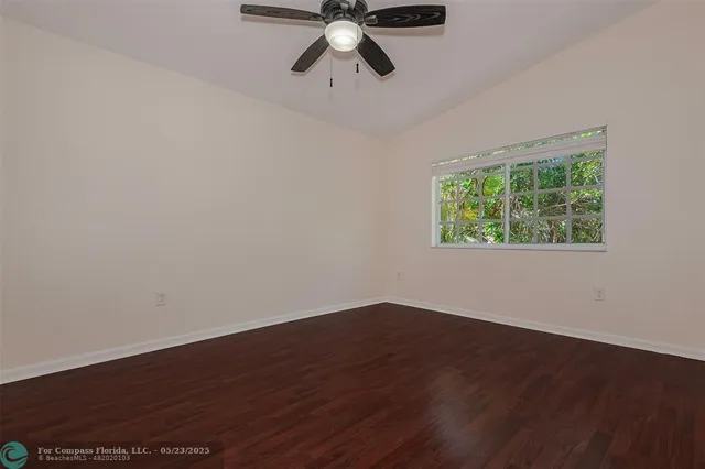 a view of empty room with wooden floor and fan