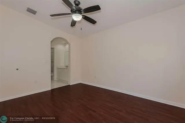 an empty room with wooden floor ceiling fan and window