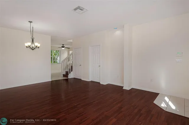 a view of empty room with wooden floor and ceiling fan
