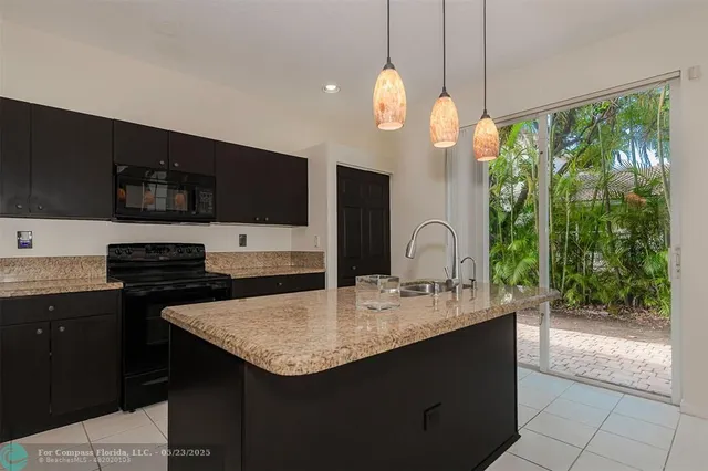a kitchen with kitchen island granite countertop a sink and a stove