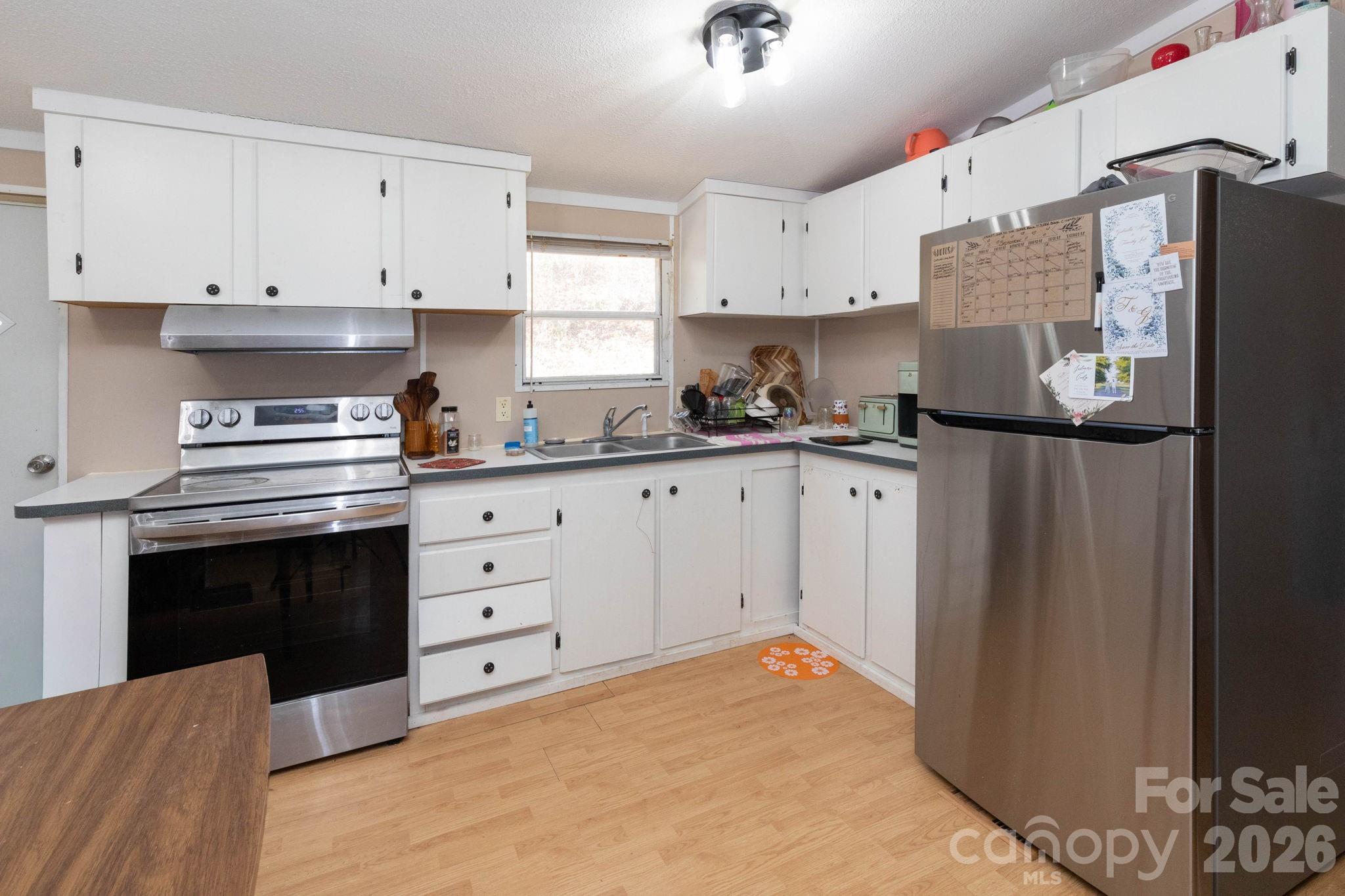 143 Hubert McCall Drive Balsam Grove, NC 28708 - Photo 6 of 21 a kitchen with stainless steel appliances a stove a refrigerator and white cabinets