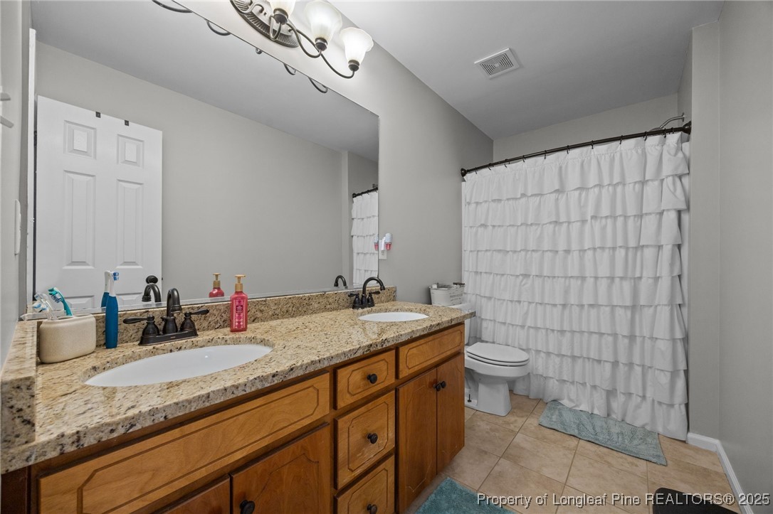 262 River Birch Run Coats, NC 27521 - Photo 38 of 49 a bathroom with a granite countertop sink a toilet and mirror